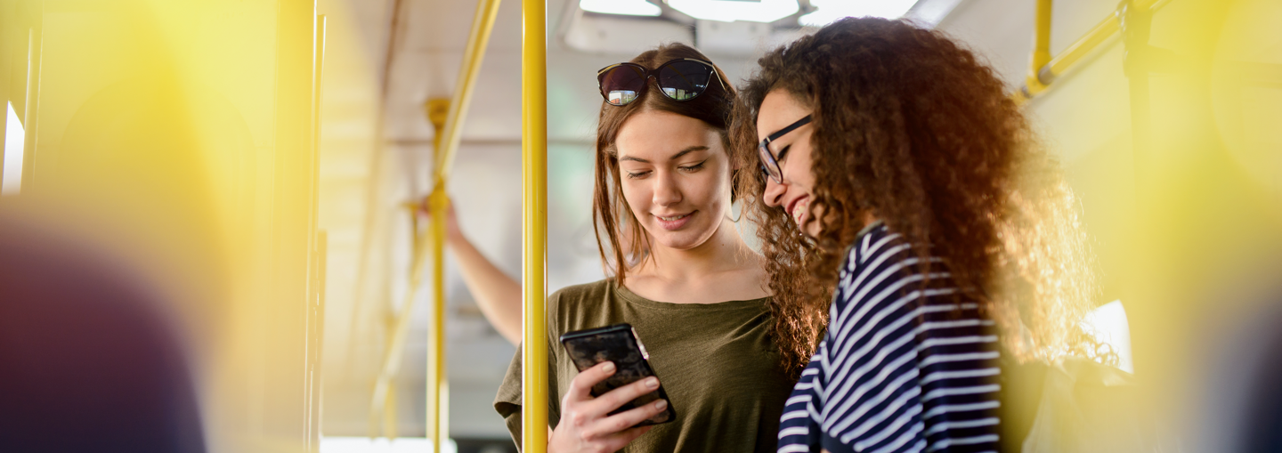 Two women on a bus looking at a smartphone