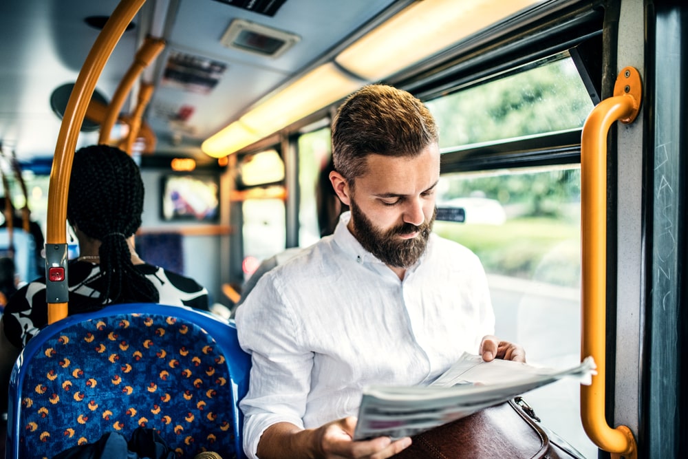 Image of man on a bus reading a newspaper